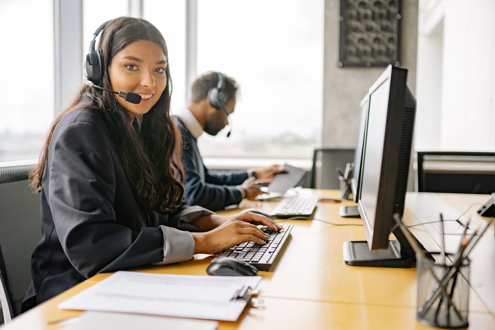 Sales and support professional at a desk with headset and keyboard — customer conversations grounded in live CRM context